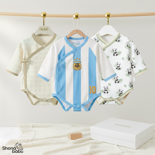 Three baby bodysuits hanging on a wooden rod with gold hooks against a light neutral wall. The center bodysuit is white with light blue vertical stripes and an Argentina football crest, flanked by a cream patterned bodysuit on the left and a white panda-print bodysuit on the right.